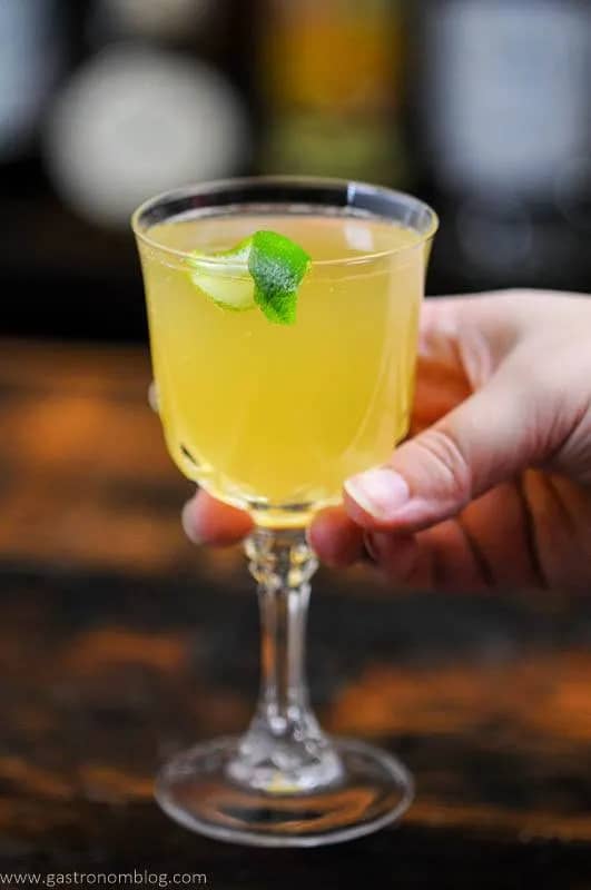 A yellow cocktail in a glass with a stem.