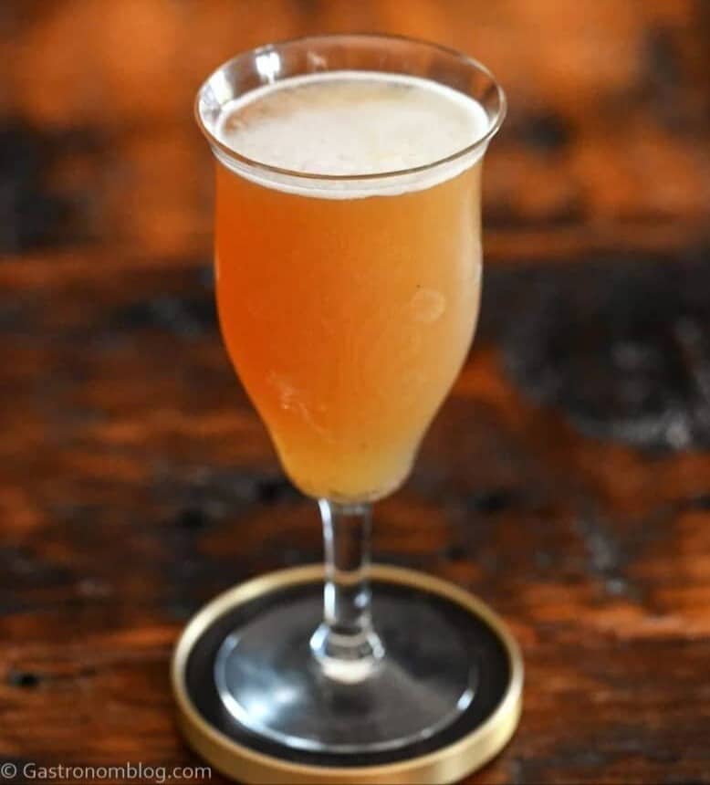 A stemmed glass holds a drink on a round coaster.