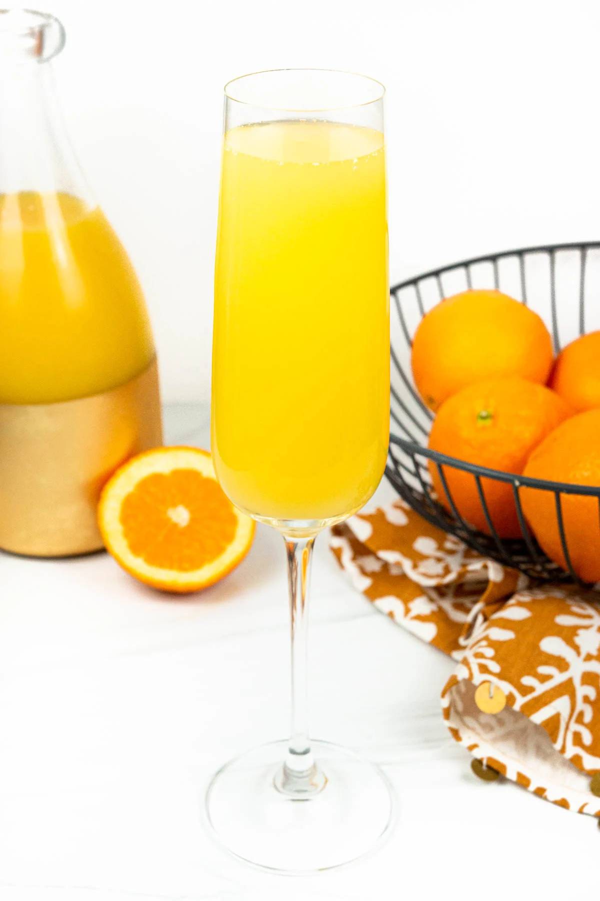 A mimosa near a bowl of oranges.