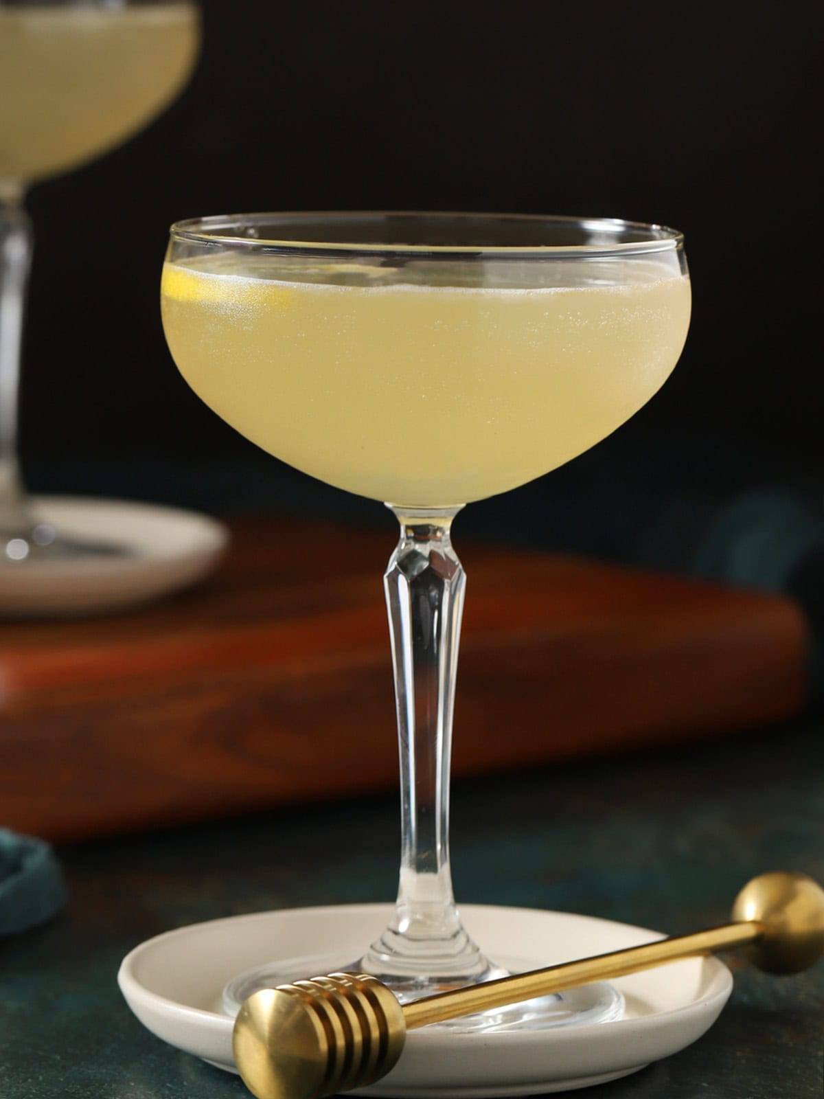 A stemmed glass holds a pale yellow cocktail.