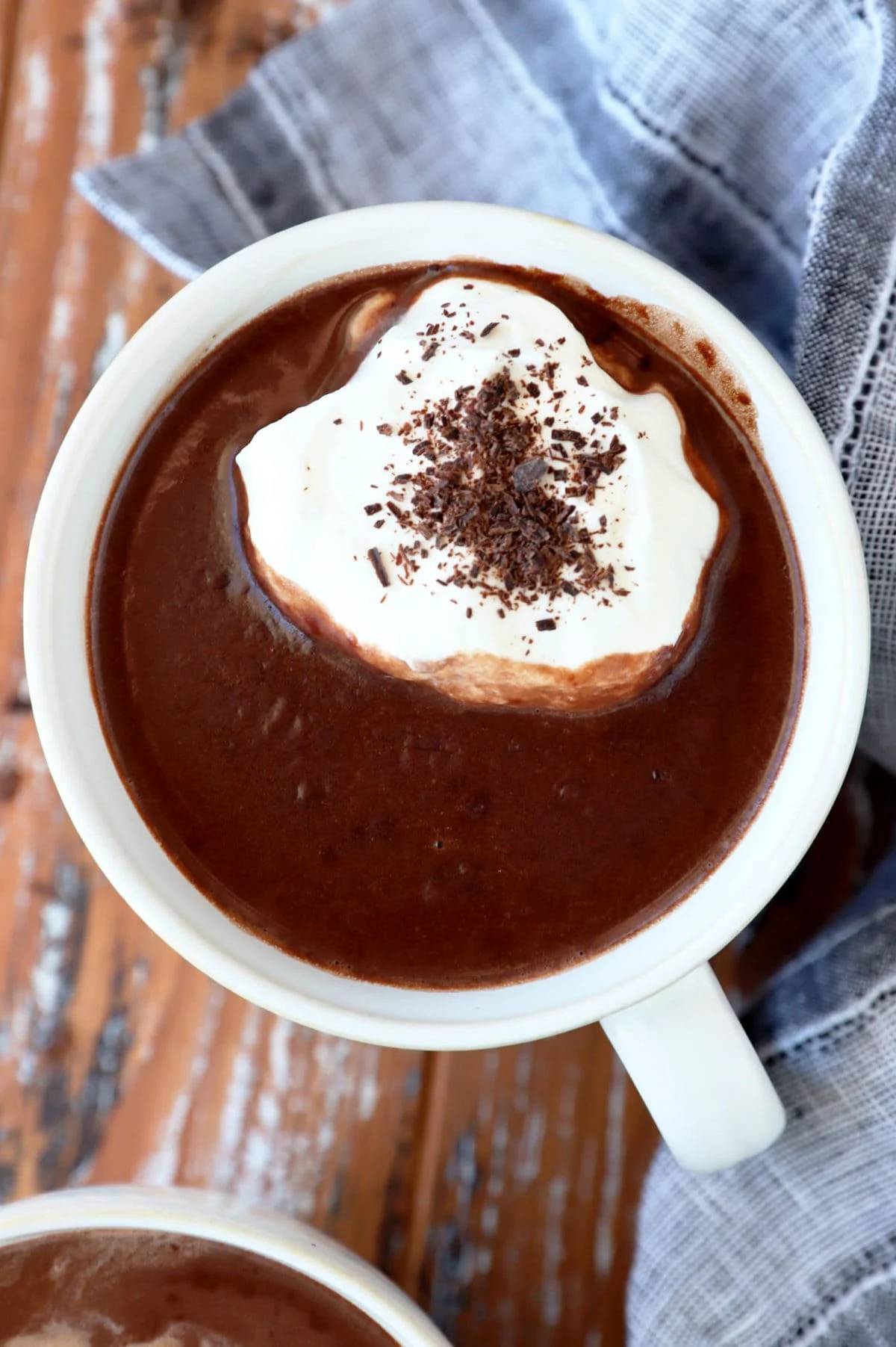 Overhead view of a white glass mug filled with hot chocolate and a dollop of whipped cream with chocolate sprinkles.