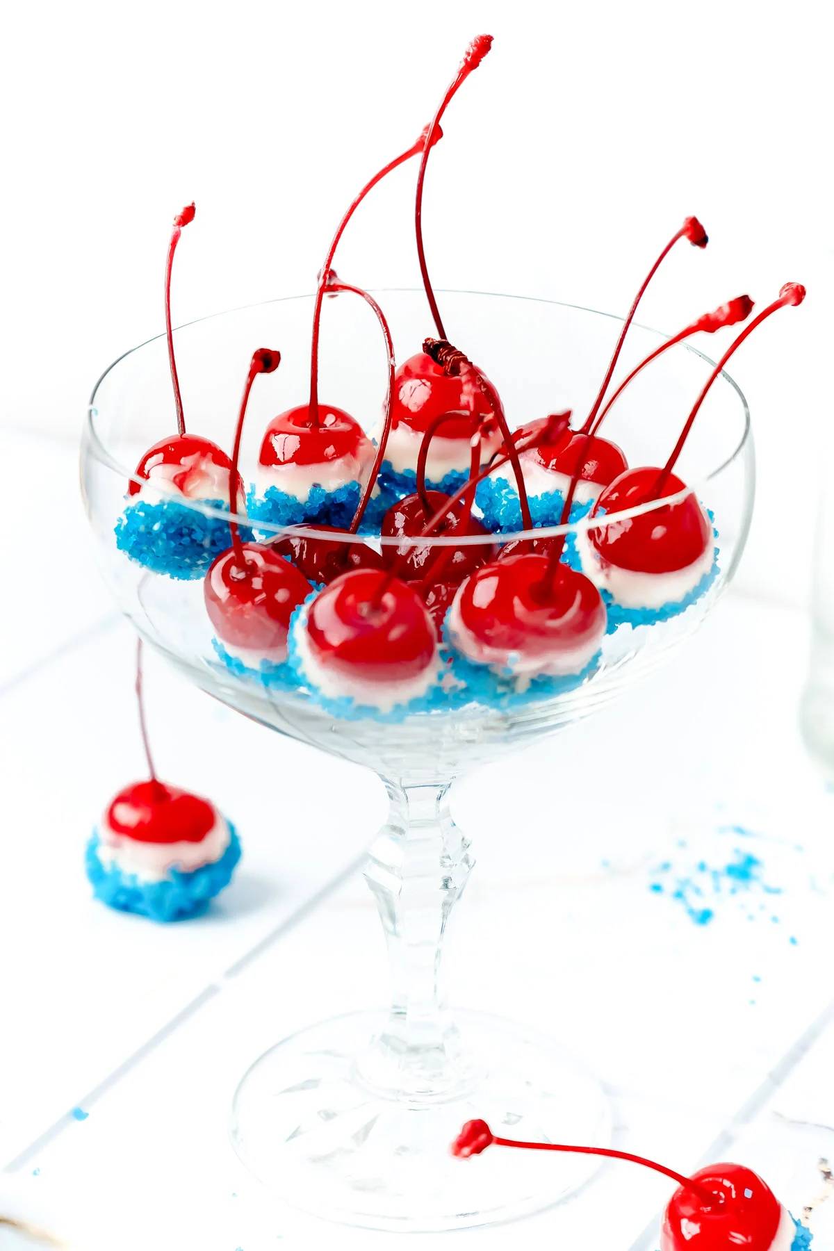 Cherries coated in white chocolate and blue sprinkles.