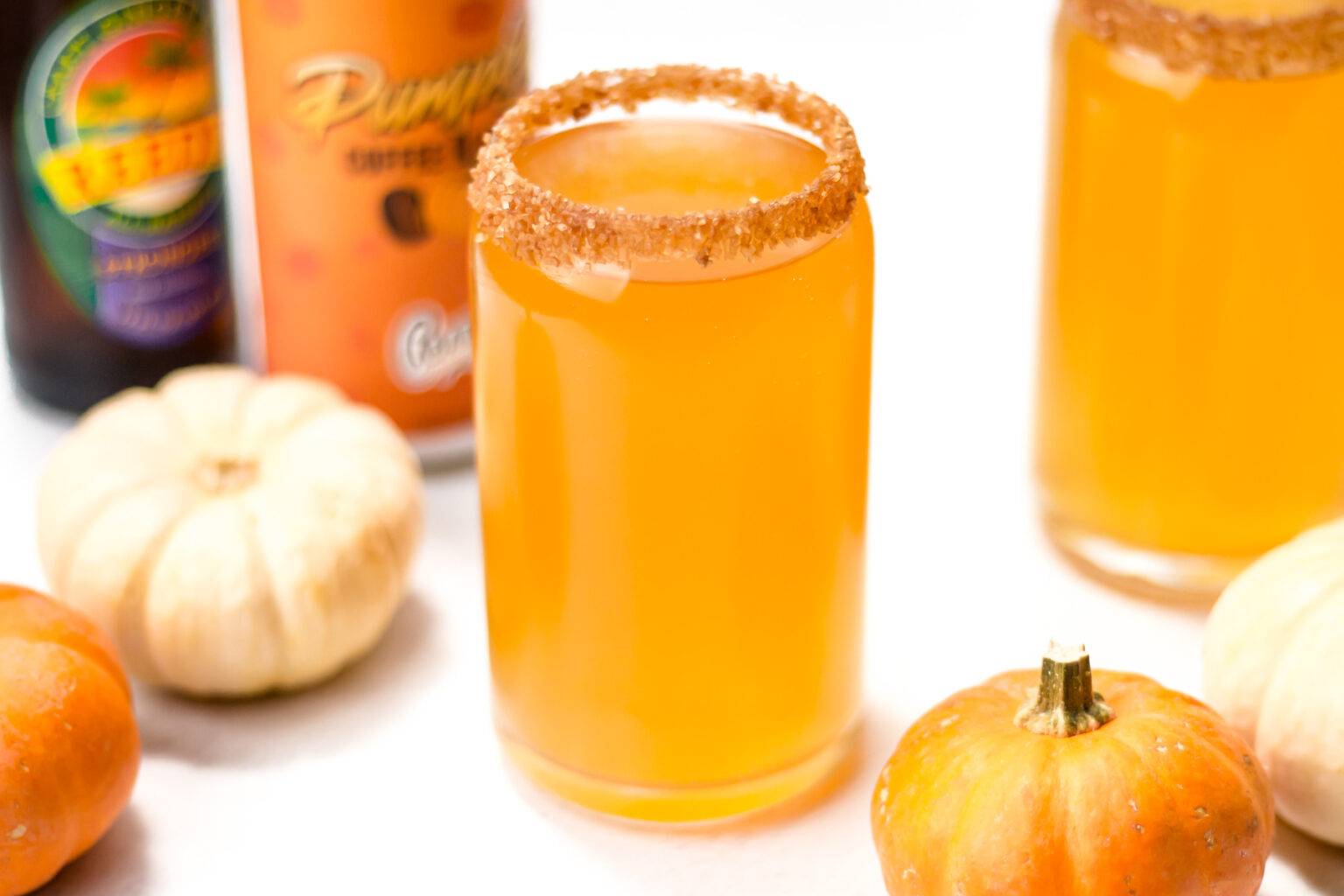 A can glass holds an orange drink rimmed in cinnamon sugar.