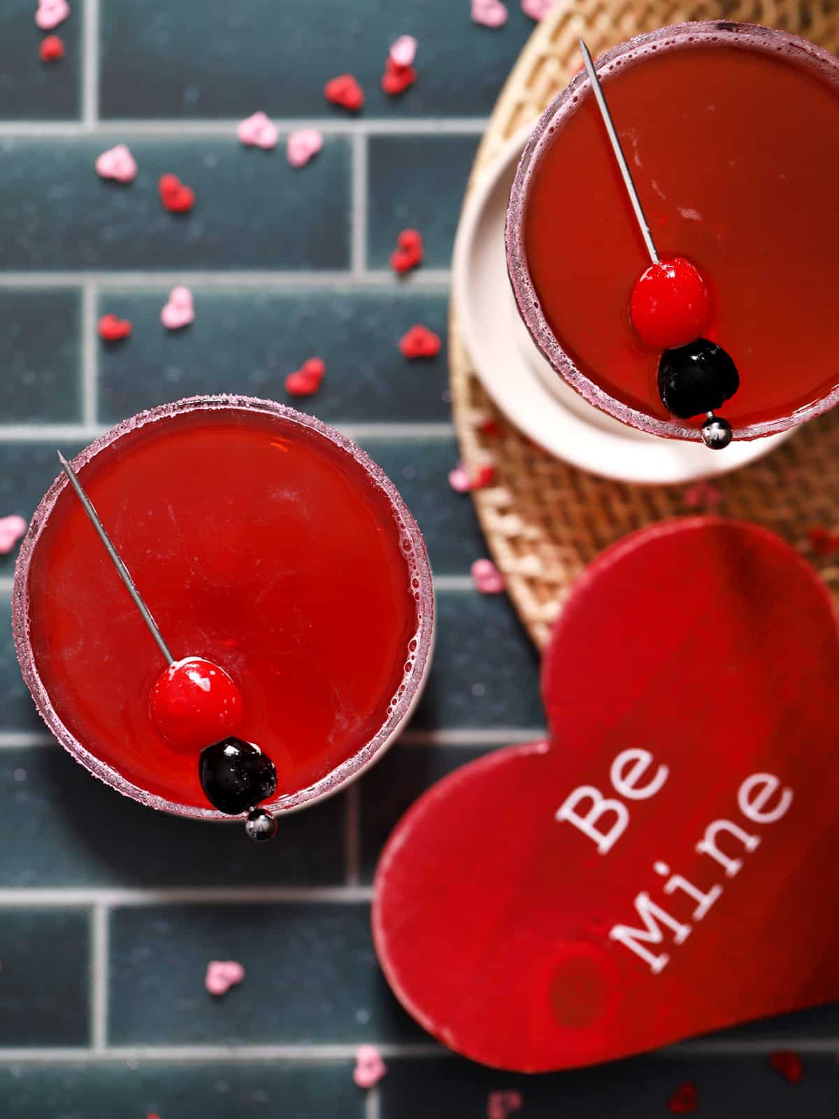 Two red drinks near a heart that says 'Be Mine.'