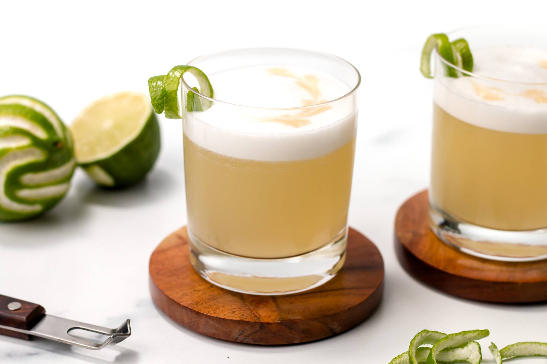 Two frothy drinks on round wooden coasters.