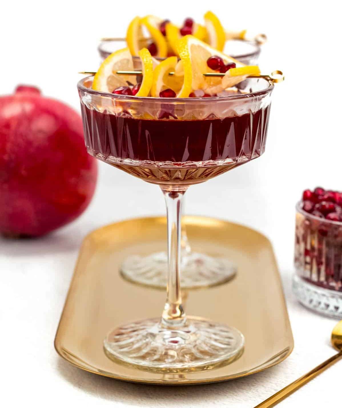Two pomegranate martinis on a gold oval tray.