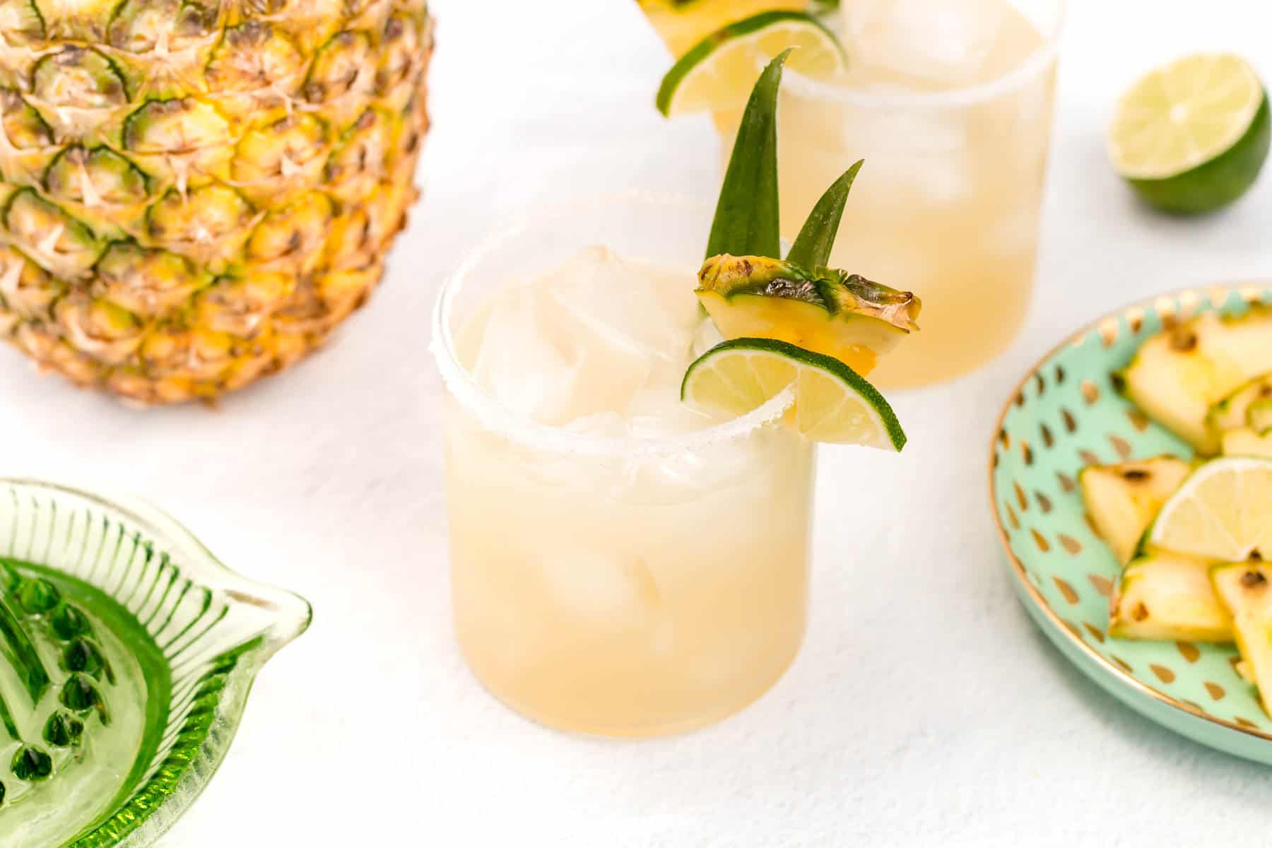 A pineapple margarita with a lime slice and margarita slice on the rim.