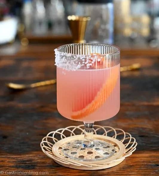 A pink grapefruit margarita on a wooden surface.