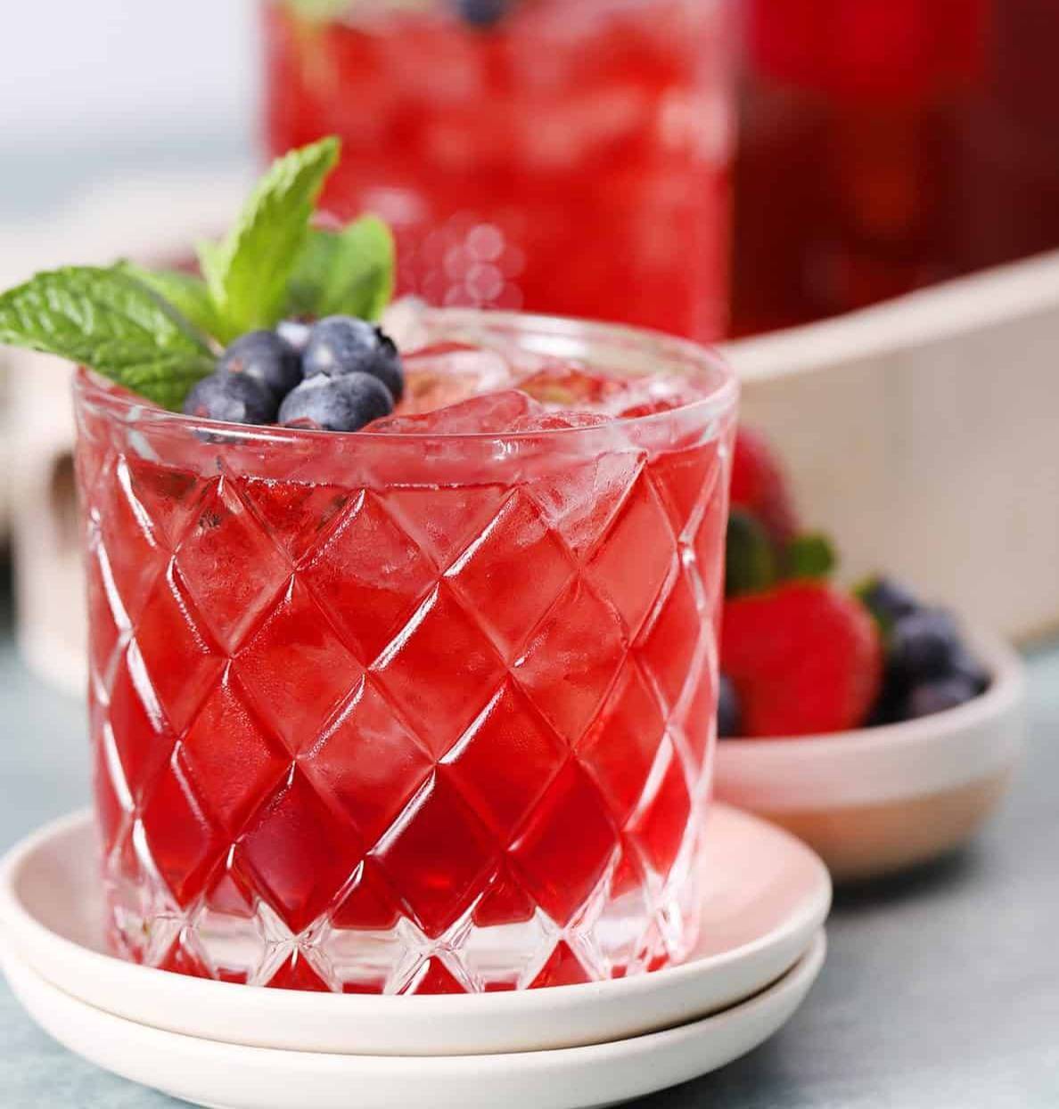 A red drink sits on round white coaters.