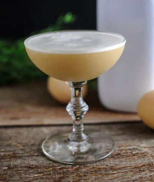 A stemmed coupe glass with a foamy pale cocktail.