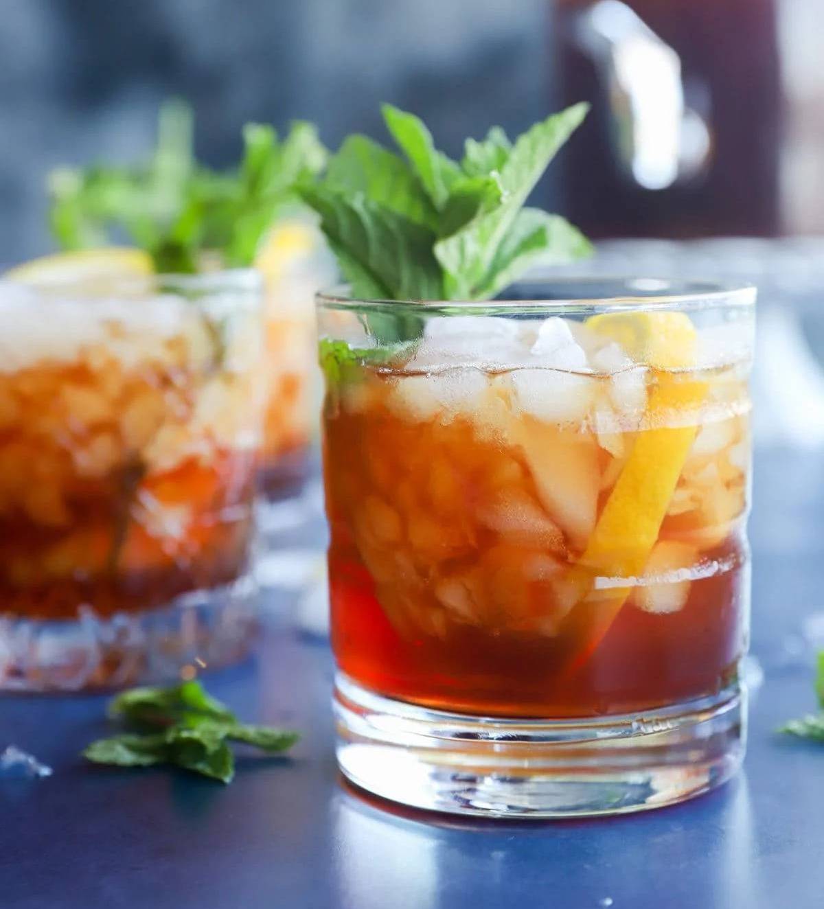 An amber cocktail garnished with an herb sprig.