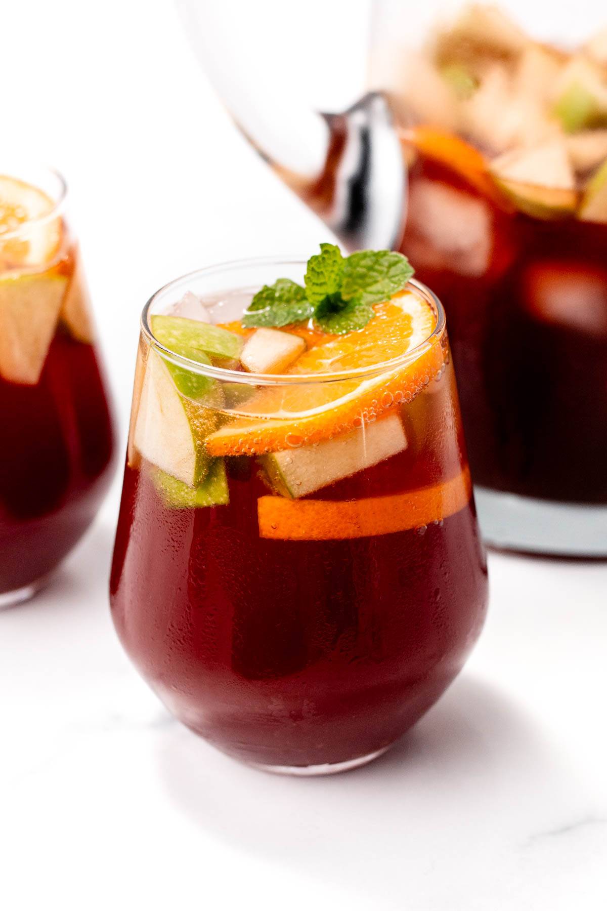 A deep red drink topped with fruit slices.