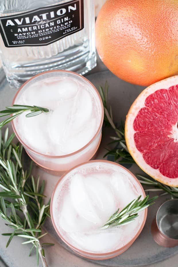 Overhead view of two drinks next to a halved grapefruit.