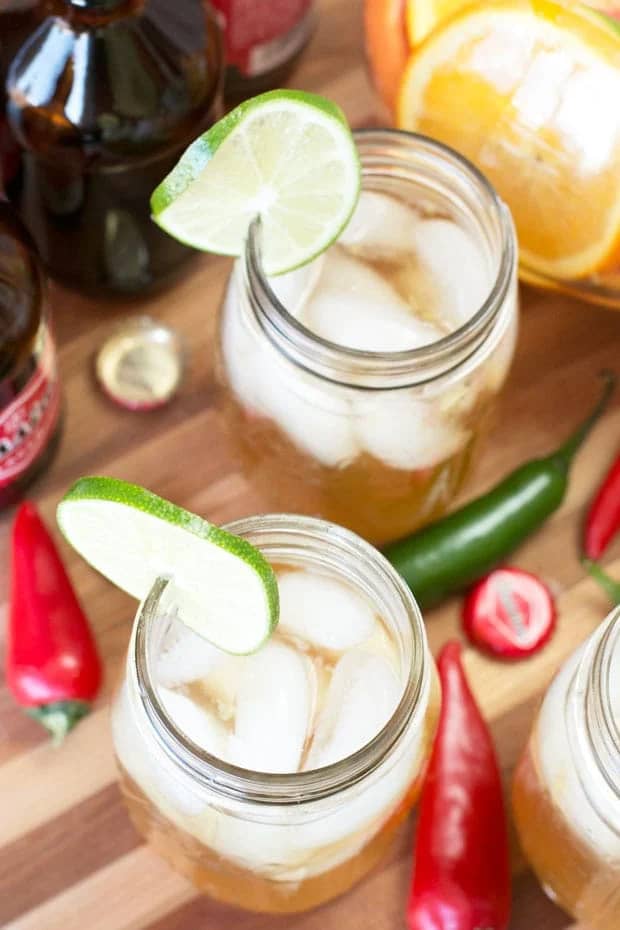 Overhead view of a beer sangria in mason jars near whole green and red chiles.