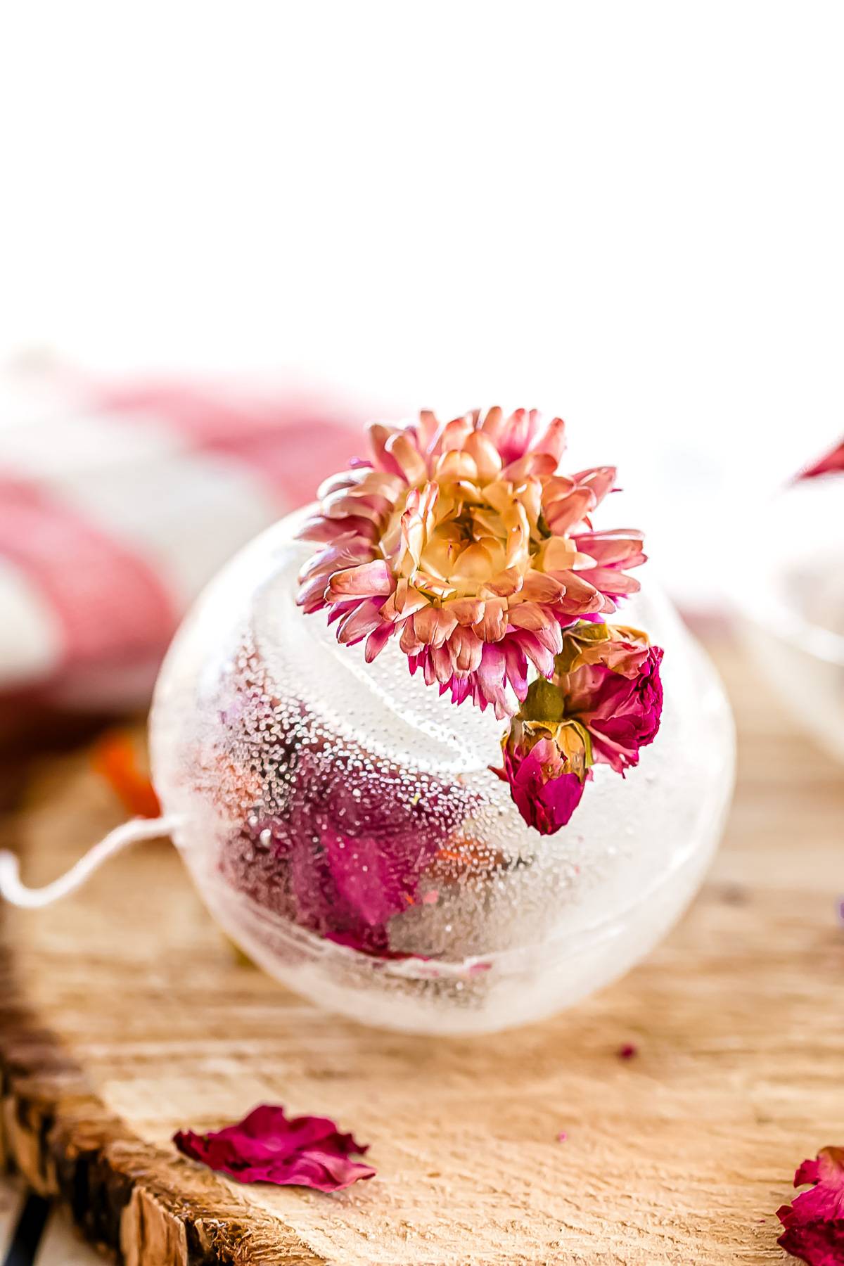 A sugar ball with dried flowers sitting on a wooden surface.