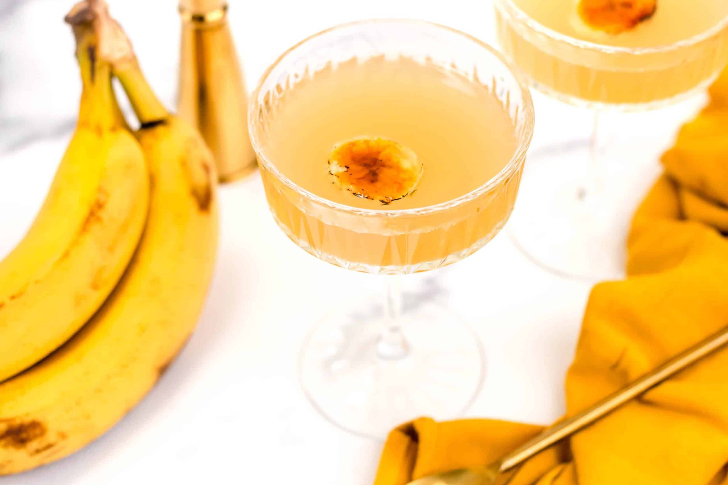 A yellow banana drink near a bunch of bananas.