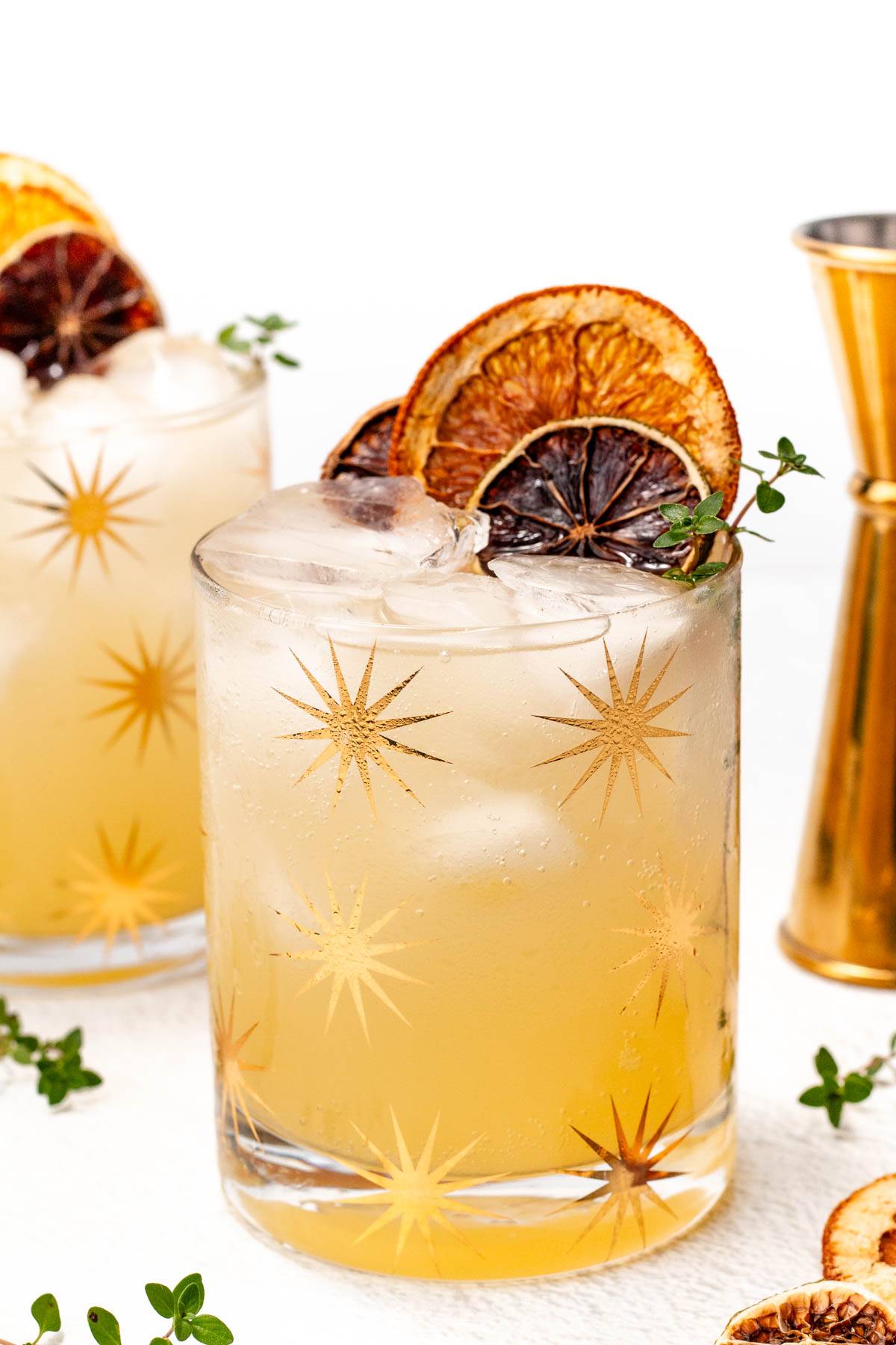 Two yellow drinks topped with dried citrus rounds.