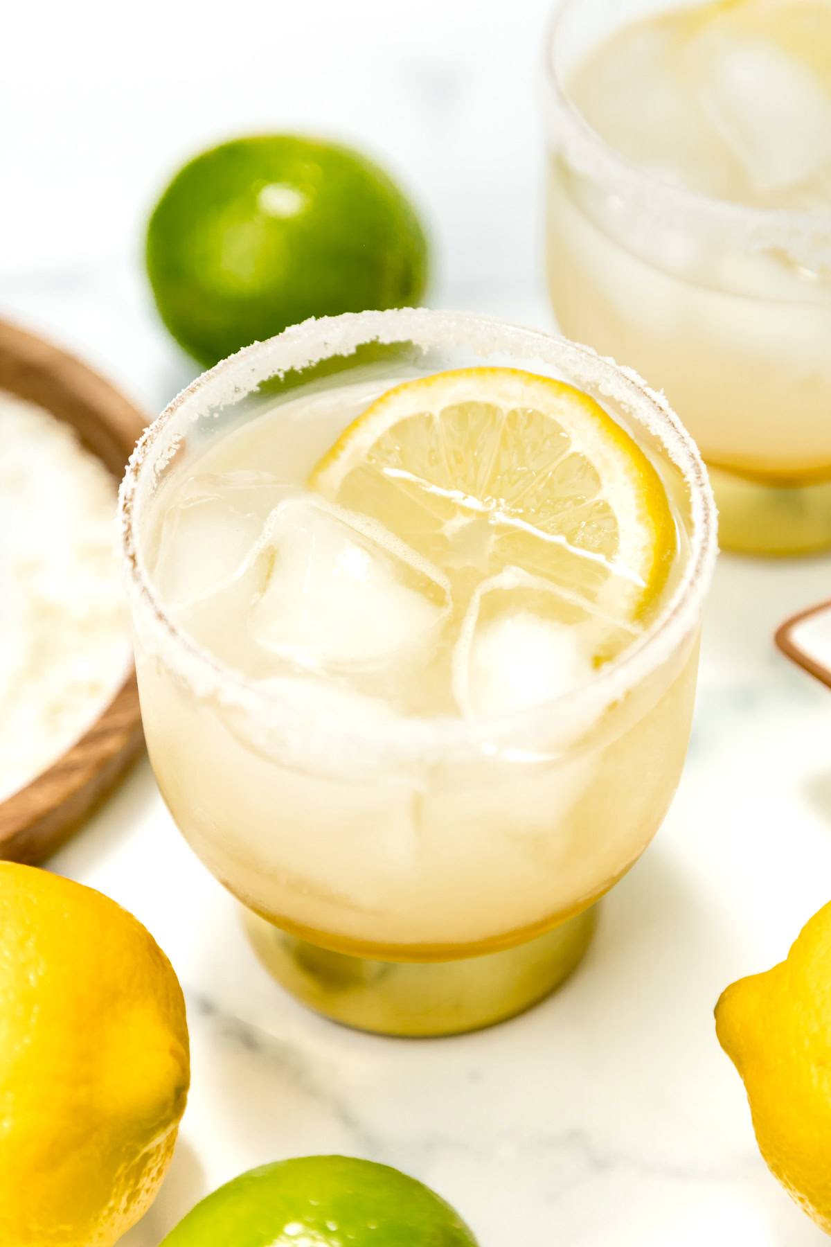 A lemon margarita near whole lemons and limes.