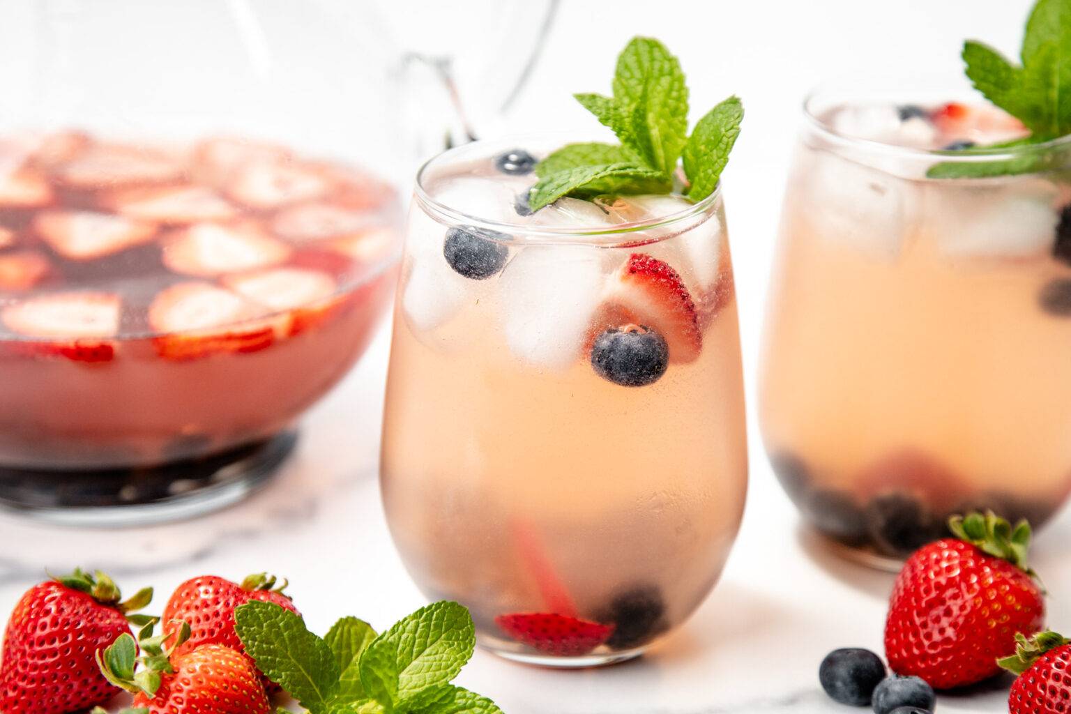 A stemless wine glass holds a white sangria with berries.
