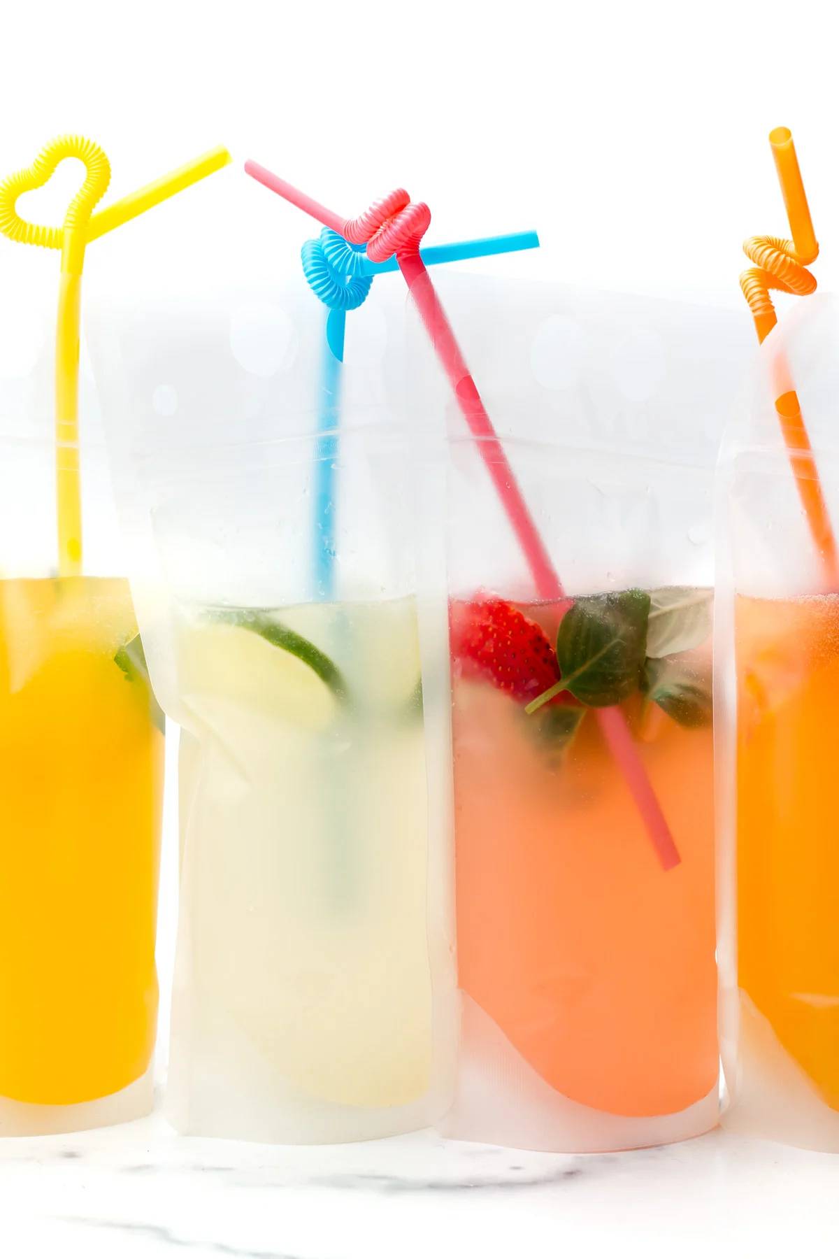 Cocktail pouches with colorful straws sit in front of a white background.