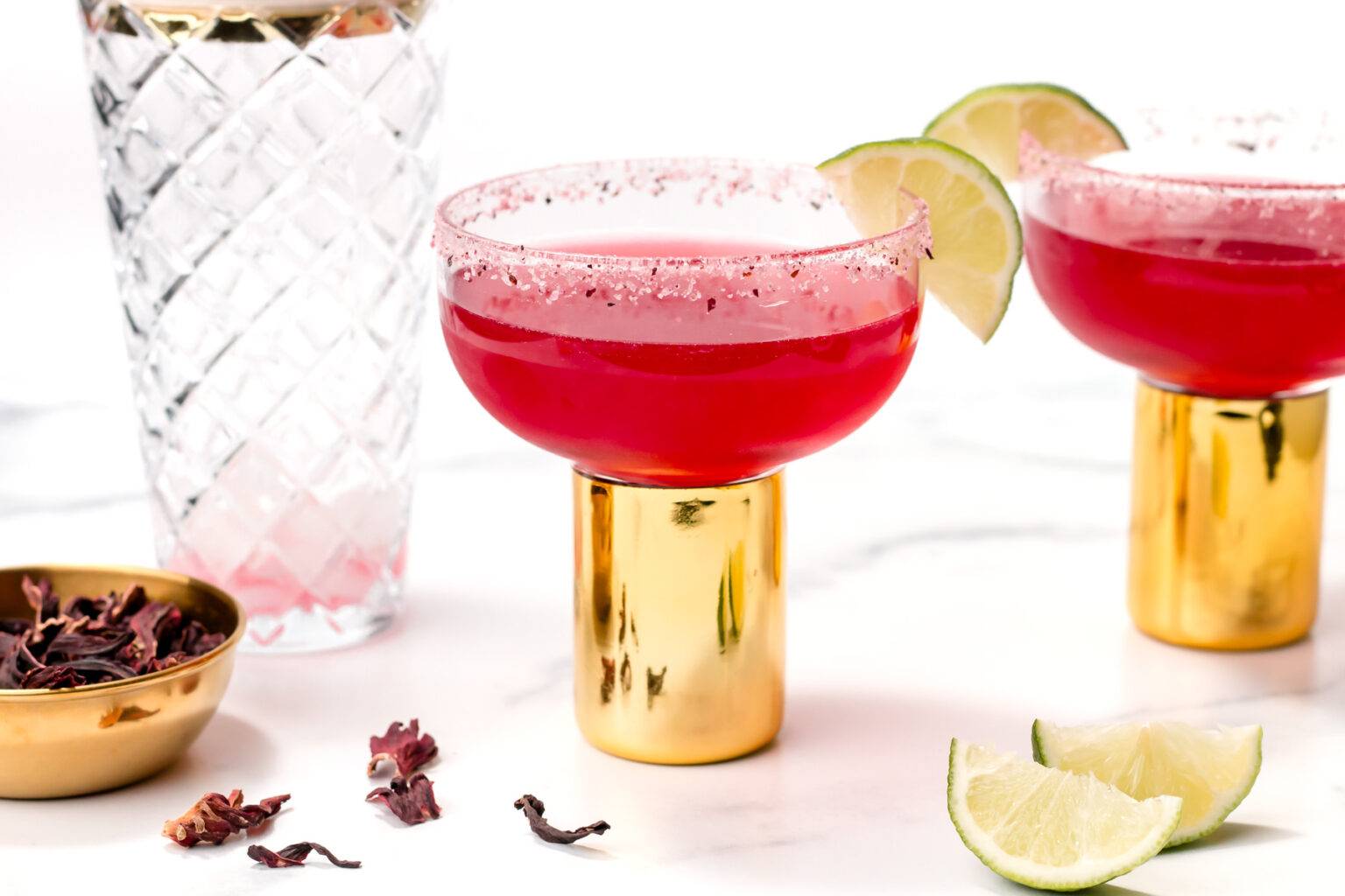 A red margarita in a glass with a gold stem.