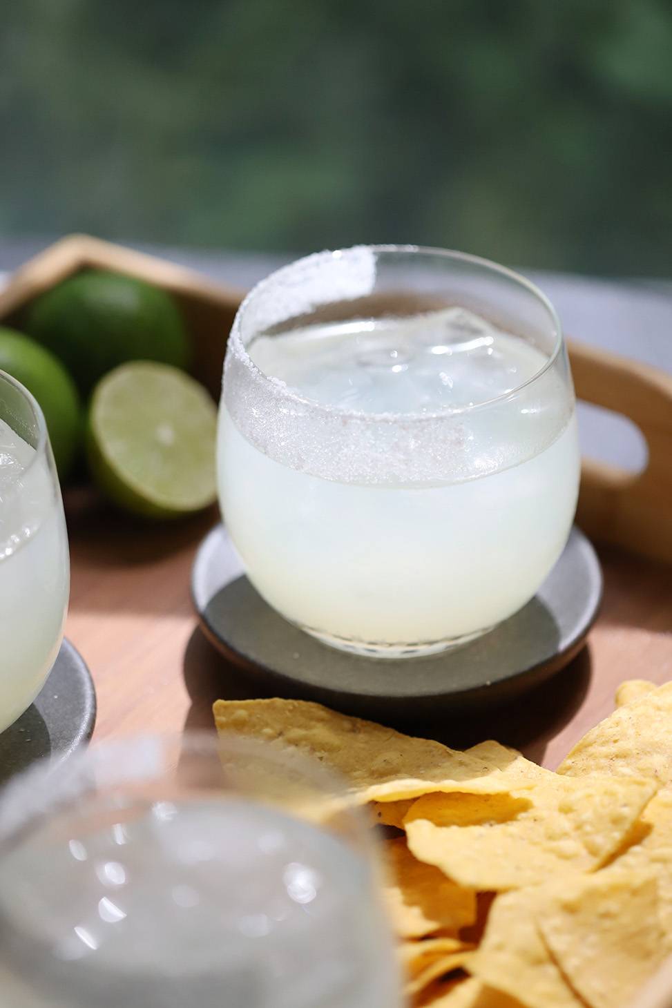 A margarita with a salted rim near tortilla chips and limes.