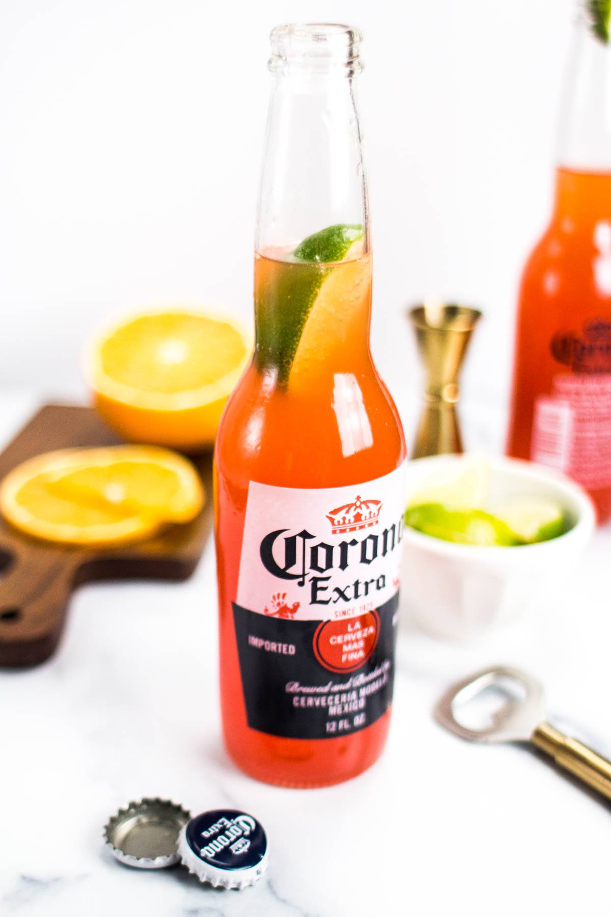 An ombre orange drink made in a Corona bottle with a lime wedge in the neck.