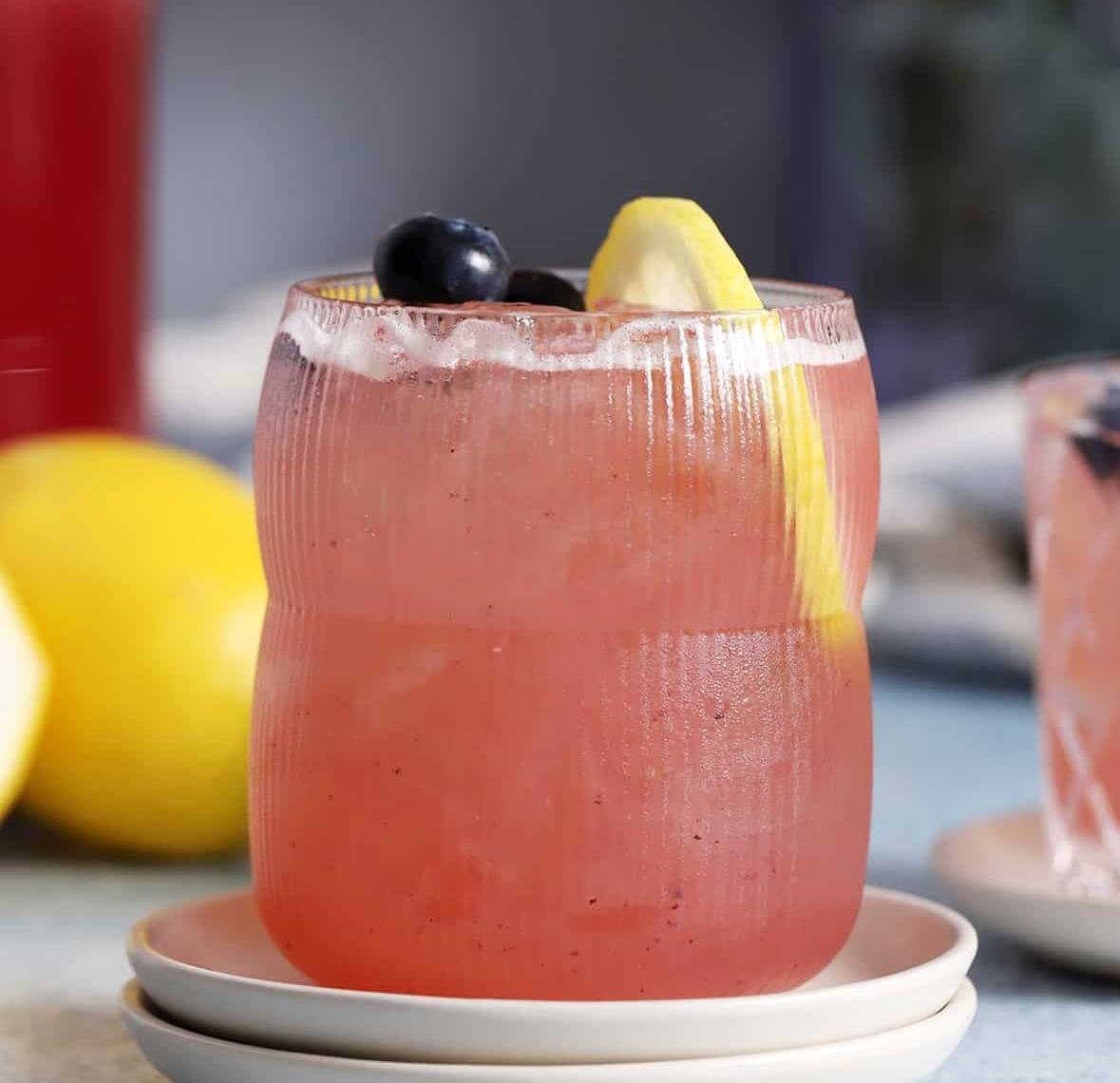 A light purple drink with a lemon slice and blueberries.