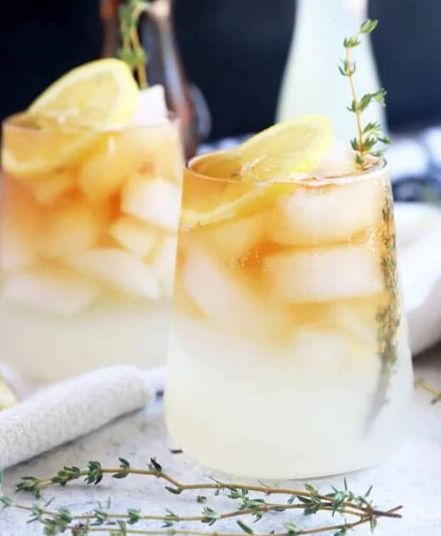 A glass holds a lemonade iced tea drink with a lemon round.
