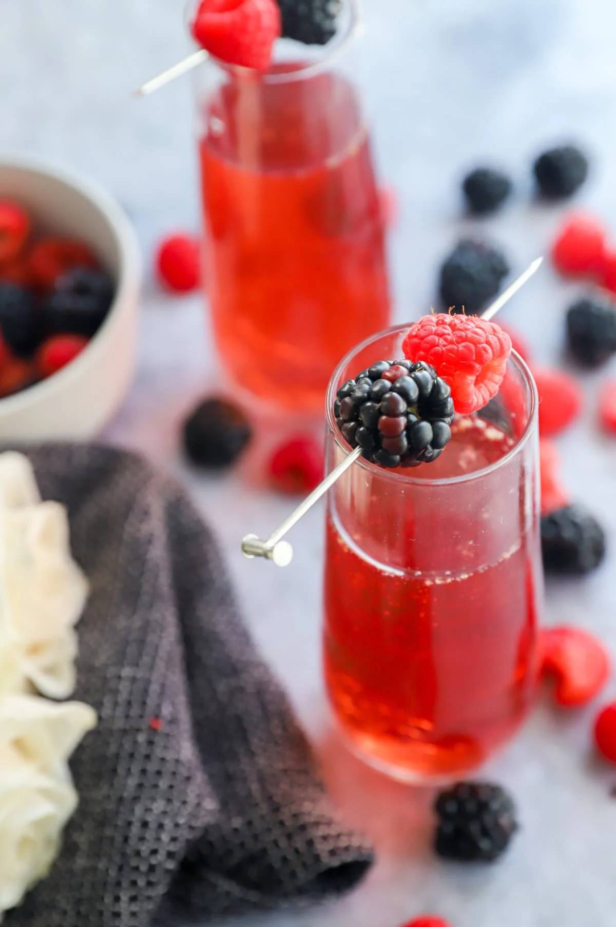 Overhead view of a red drink garnished with a gold cocktail pick holding a blackberry and raspberry.
