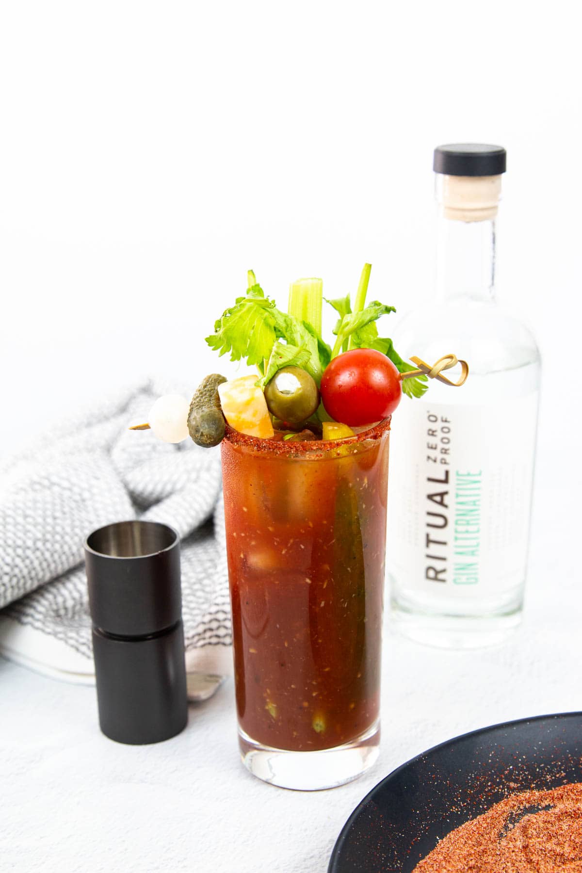 A bloody Mary sits in front of a bottle of Ritual zero-proof vodka.
