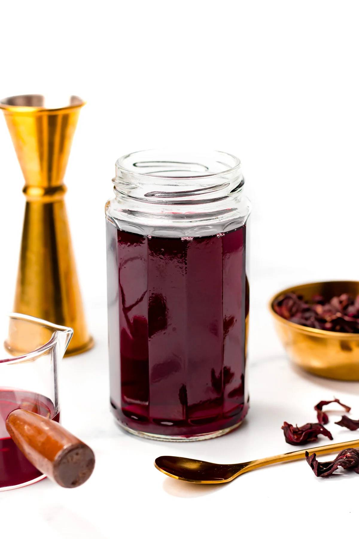 A jar of deep red syrup near gold bar tools.