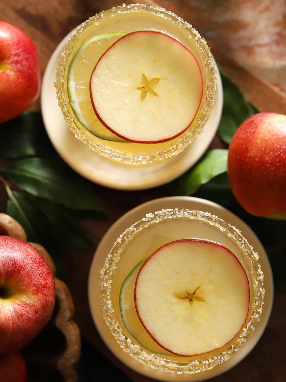 Overhead view of apple rounds floating in an apple cocktail near whole apples.