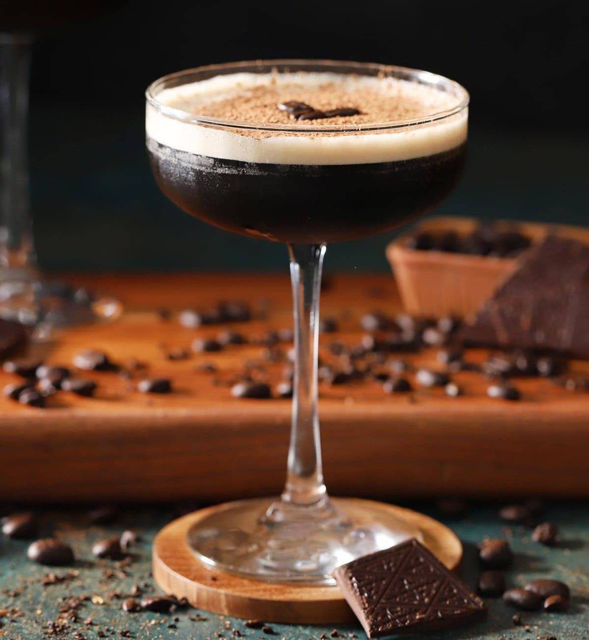 A chocolatey brown cocktail in a stemmed coupe glass.