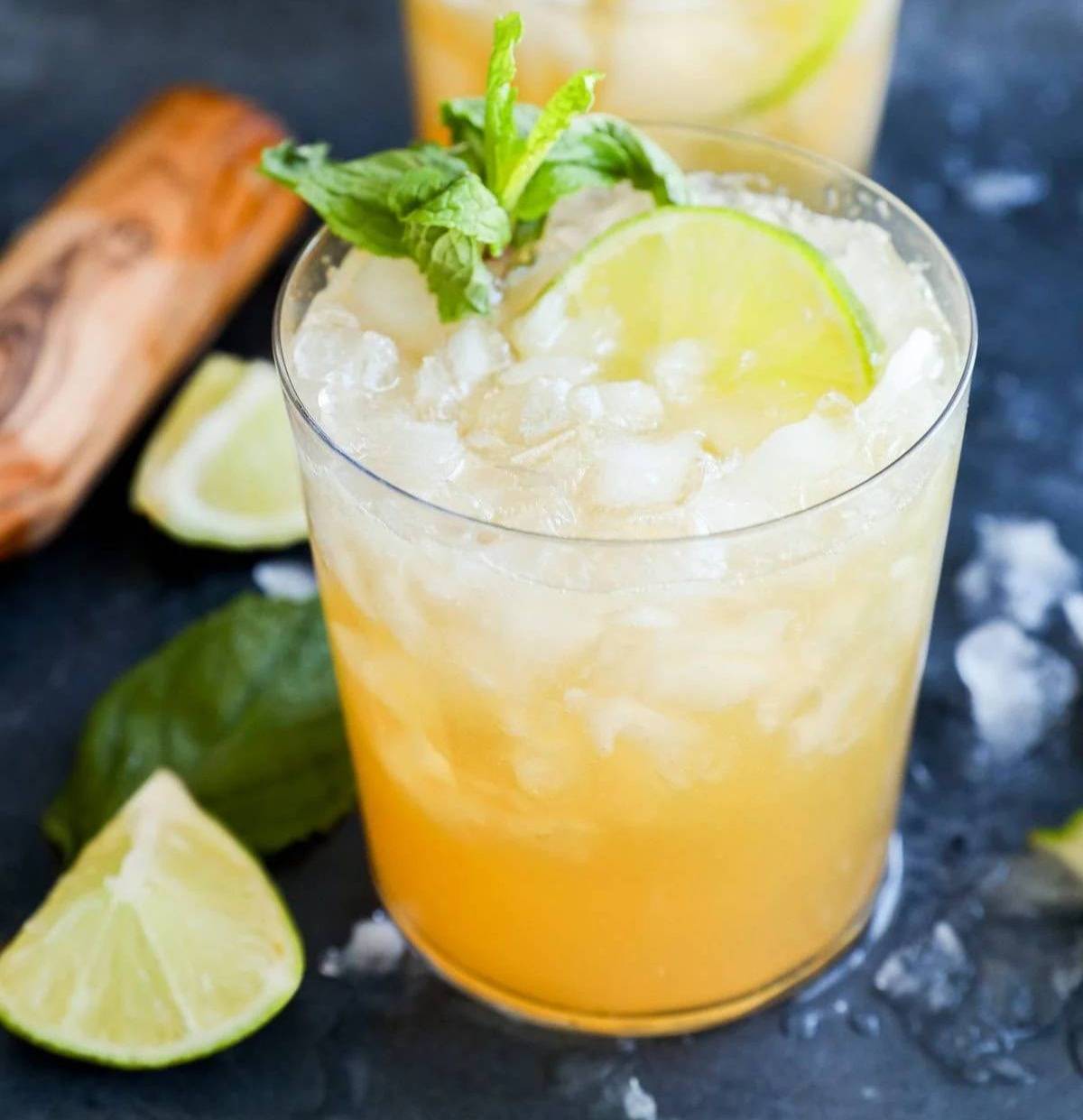 A yellow drink with crushed ice and a lime.