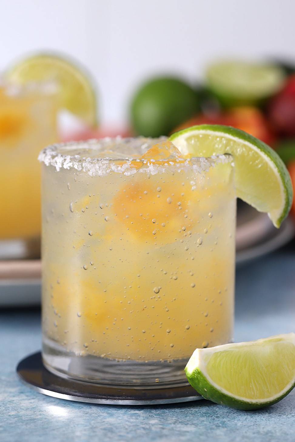 A rocks glass holds a light yellow cocktail with a salt rim and a lime slice on the rim.