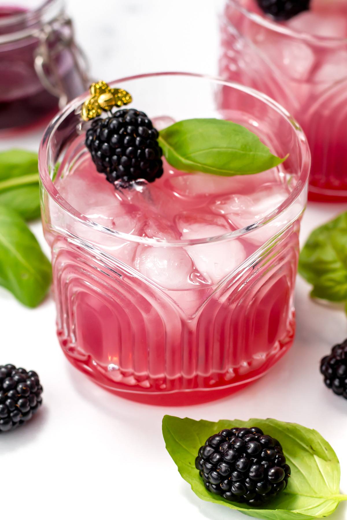 A deep purple drink garnished with a blackberry and a basil leaf.