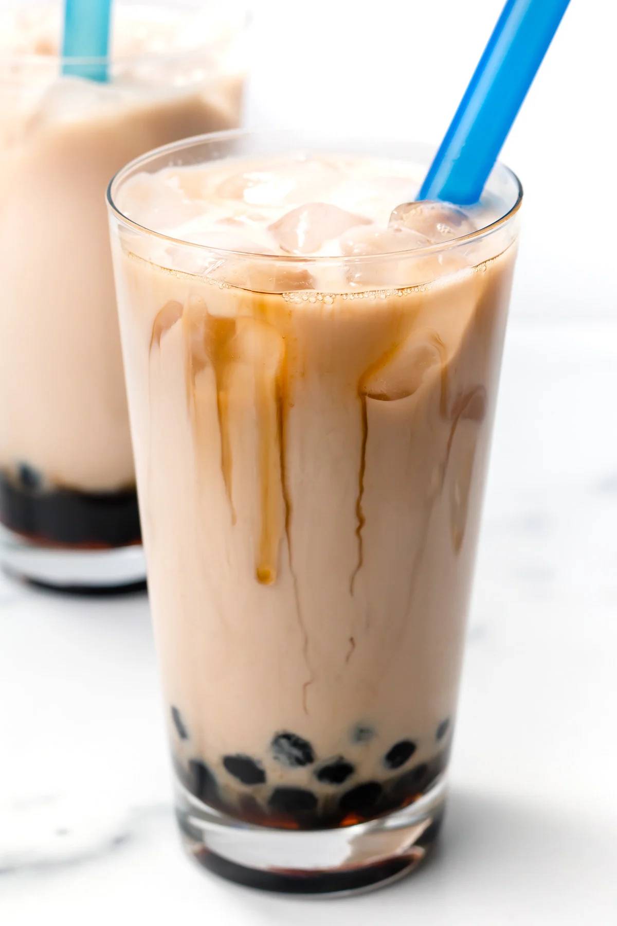 A creamy glass of tea with caramel drizzle and boba at the bottom of the glass.