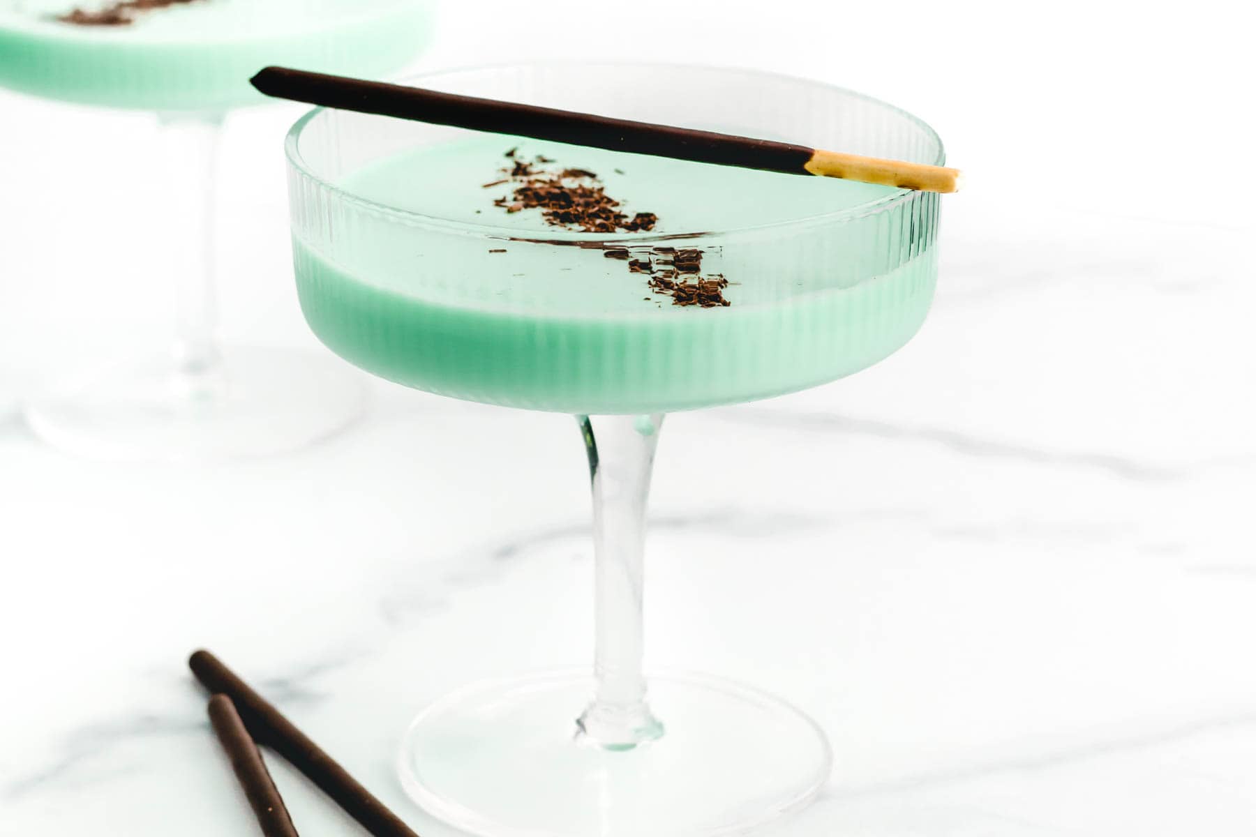 Mint green drink topped with chocolate sprinkles and a chocolate dipped cookie rod.