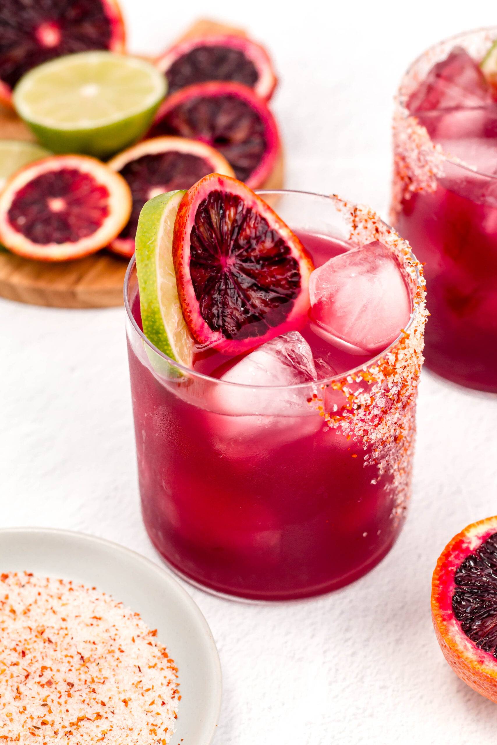 A blood orange margarita in a glass with citrus rounds.