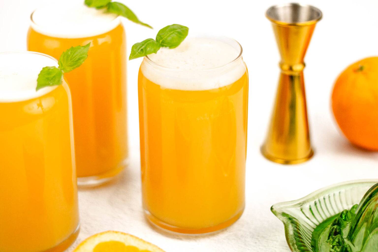 A beer cocktail in a can glass topped with a sprig of herbs.