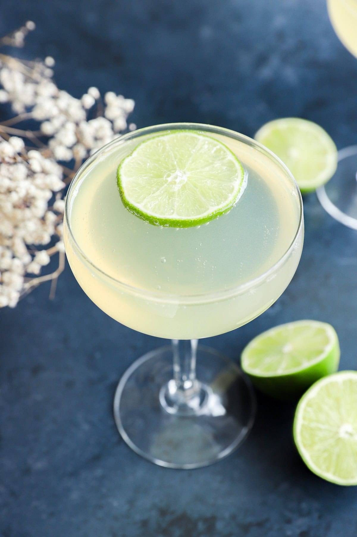 A pale green drink in a stemmed glass topped with a lime round.