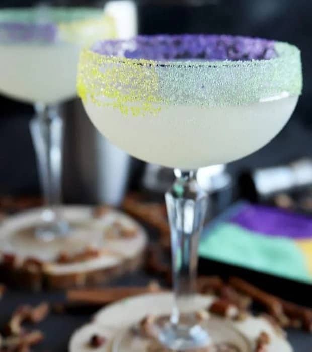 A stemmed glass rimmed in green, yellow and purple sprinkles.