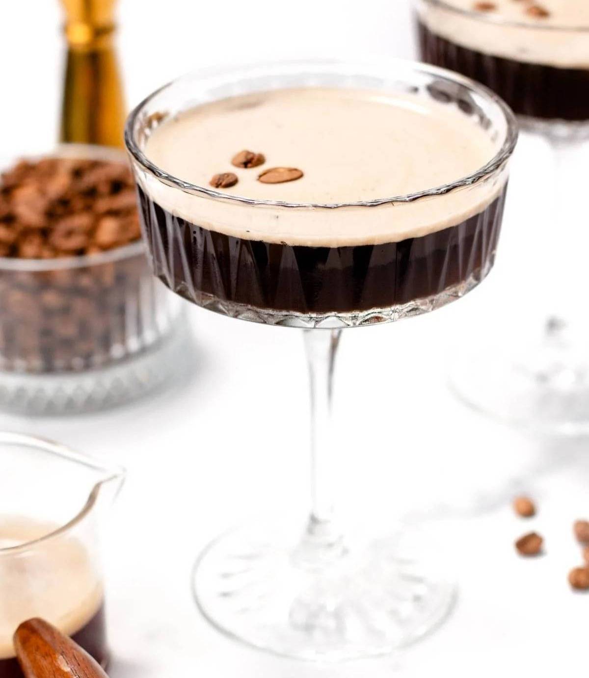 A virgin espresso martini near a glass bowl of coffee beans.