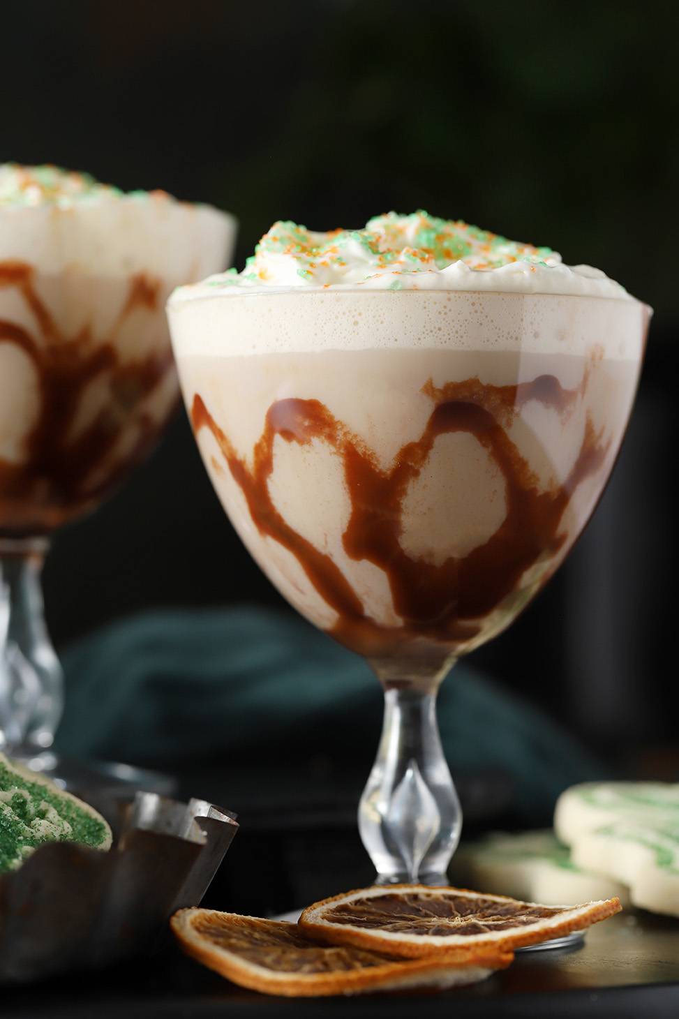 A creamy cocktail topped with foam and green and orange sprinkles.