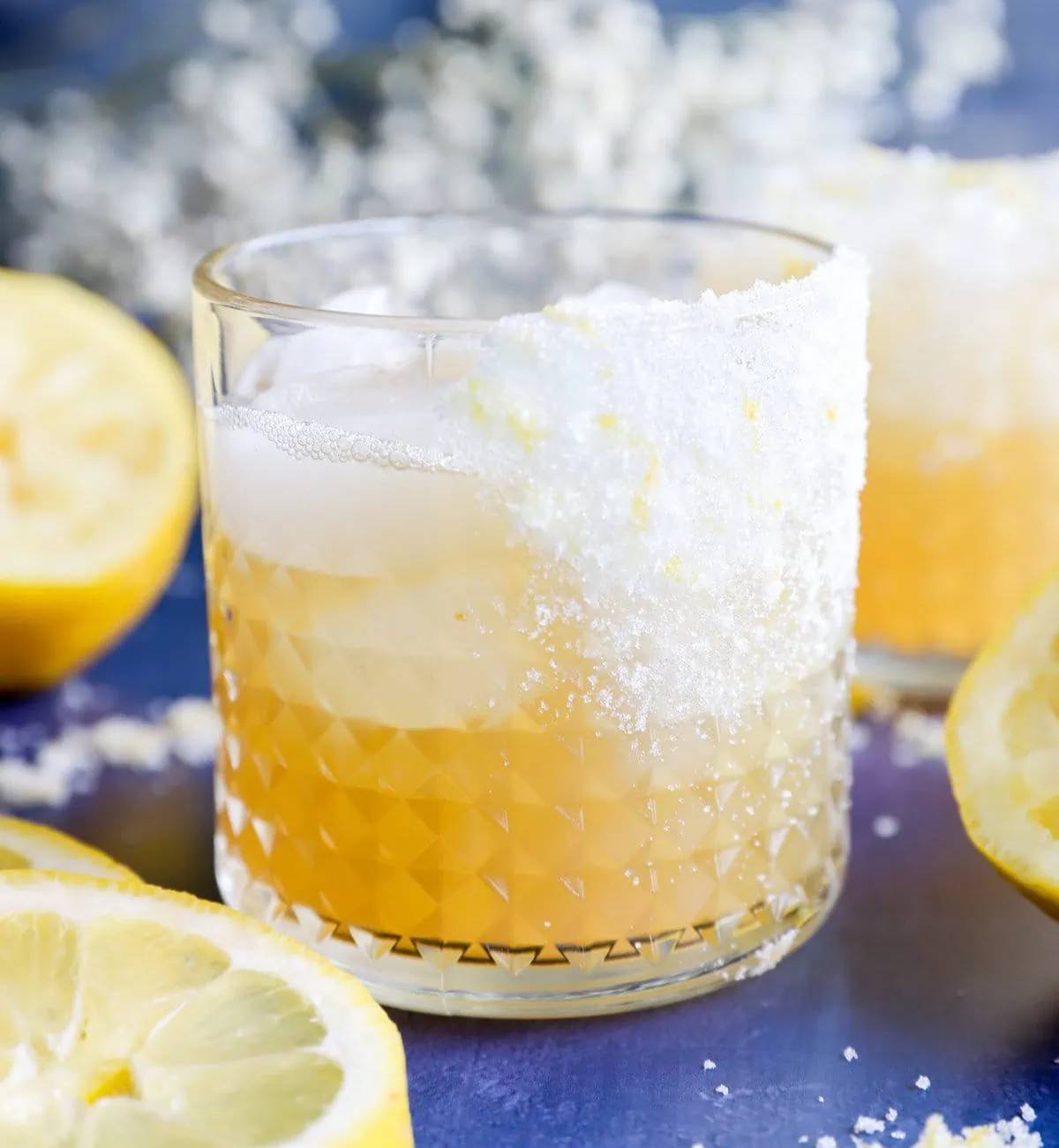 A lemon margarita in a rocks glass near sliced lemons.