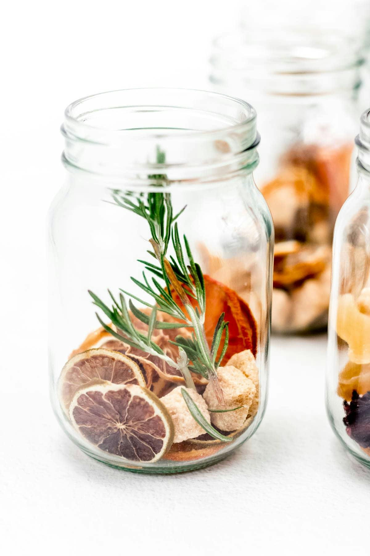 A glass jar with dried fruit, spices and sweeteners.