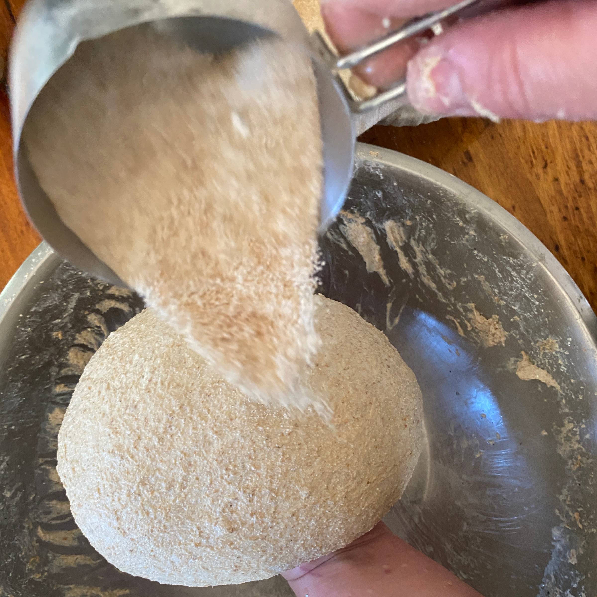 sprinkling whole wheat flour on a 100% whole wheat boule