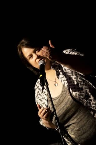Joanna Evervenn speaking into a microphone and gesturing with one hand. Image by Brendan Bonsack. 