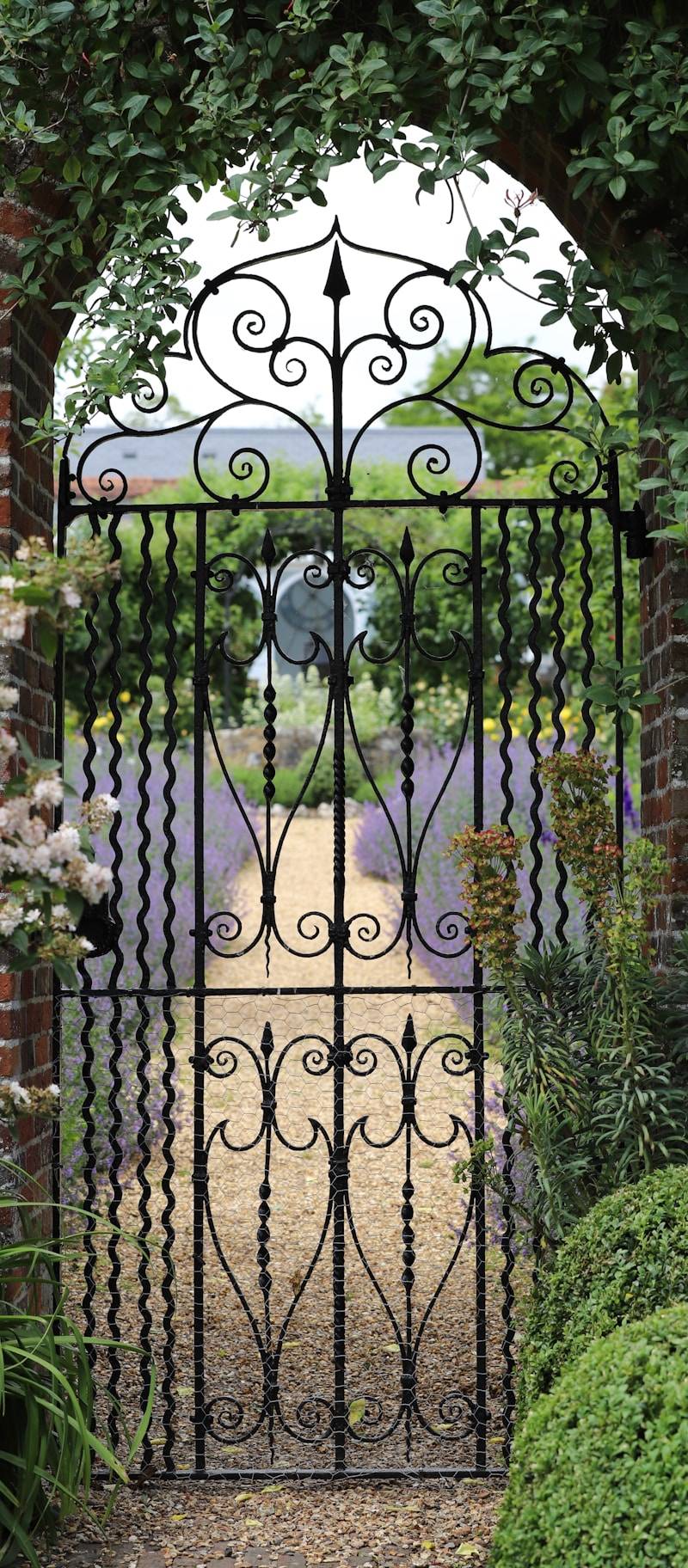 A wrought iron gate in the middle of a garden